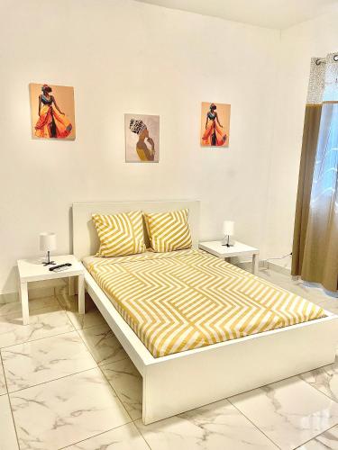 ein weißes Schlafzimmer mit einem Bett und zwei Nachttischen in der Unterkunft Villa Côte d Azur - 4 chambres, 4 TV, 4 salles de bain privatives - Internet Netflix in Mtsamboro