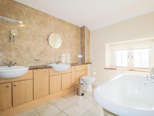 a bathroom with two sinks and a tub and a toilet at The Farmhouse in Keswick