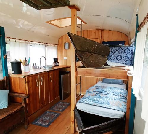 a small room with a bunk bed and a kitchen at El Destino - Rooftop Converted Chicken Bus in San Marcos La Laguna