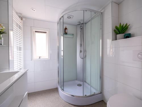 a glass shower in a white bathroom with a toilet at Ermmoon Cottage in Erm