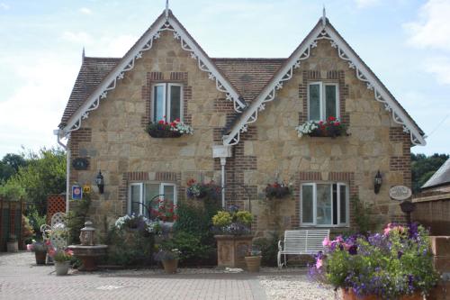 a stone house with flowers in front of it at Koala Cottage in Ventnor