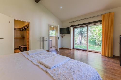 a bedroom with a large bed and a large window at Casal do Aviador in São Vicente do Paul