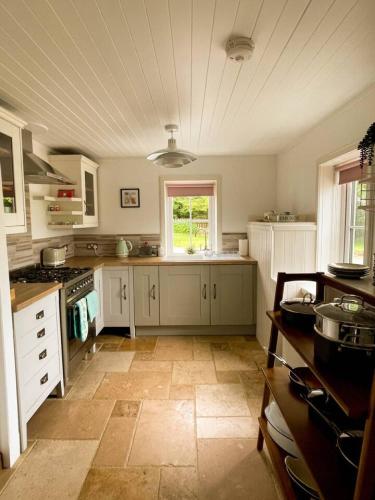 a large kitchen with white cabinets and a window at Evrabister, Shetland Islands in Mainland