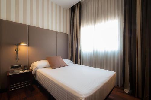 a bedroom with a white bed and a window at Zenit Valencia in Valencia