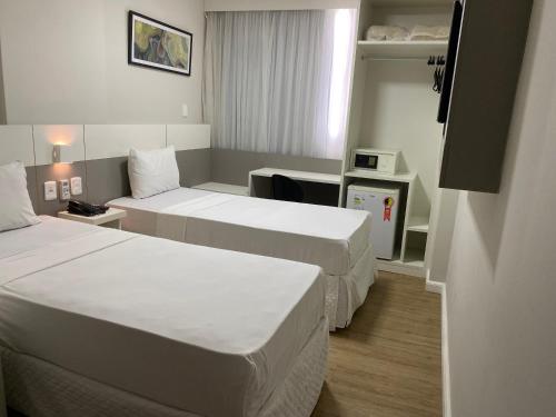a hotel room with two beds and a desk at Samba Rio Bonito in Rio Bonito
