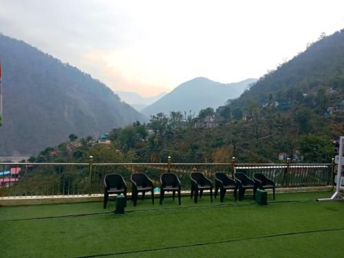 a row of chairs sitting on a balcony with mountains at Mountain View Cottage Shivpuri Rishikesh in Rishīkesh