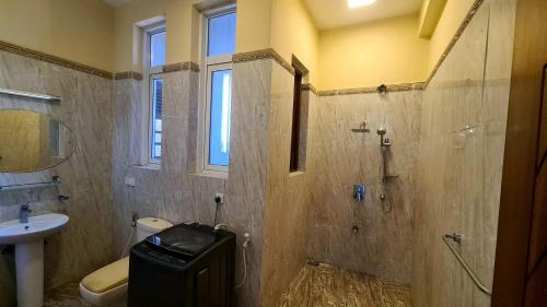 a bathroom with a shower and a toilet and a sink at Oceanway Residences in Wattala
