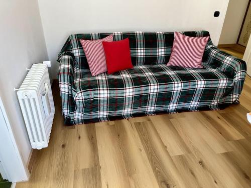 a plaid couch with two red pillows in a living room at Casa ai Dossi in Bellamonte