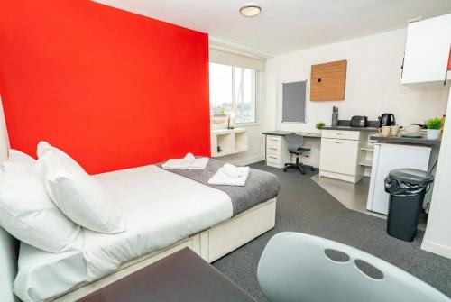 a bedroom with a bed and a red wall at Spacious & Bright Central Coventry Budget Studio in Coventry