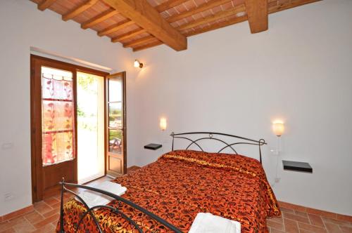 a bedroom with a bed with an orange comforter at Pienza by PosarelliVillas in Pienza