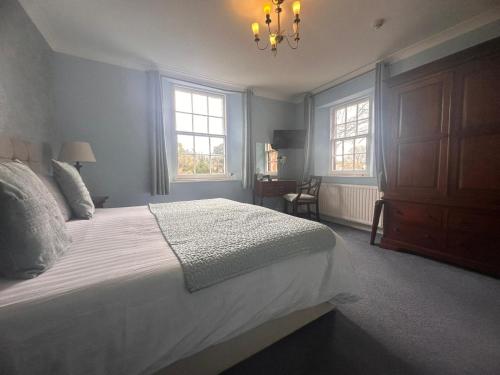 a bedroom with a white bed and two windows at Manor Inn Galmpton in Brixham