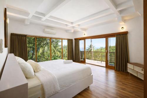 a bedroom with a large bed and a balcony at Segara Hill Villa in Senggigi