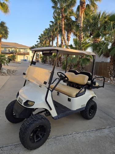 a golf cart parked on a sidewalk with palm trees at Tranquil Turtle complete with Arcade plus Pool optional Golf Cart in Port Aransas