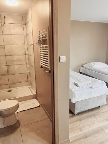 a bathroom with a toilet and a bed and a shower at Gościniec u Zawierki in Łódź