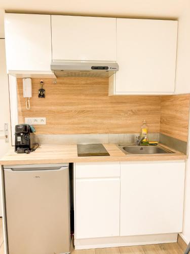 a kitchen with white cabinets and a sink at Studio - Centre Ville in Sartrouville