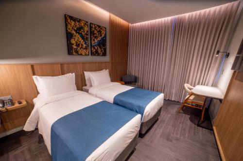 a hotel room with two beds and a chair at Slaviero Prime Campo Grande in Campo Grande