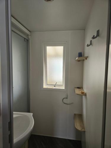 a bathroom with a bath tub and a window at Sous les Pins dans camping 4 étoiles MH familial 322 6 à 8 couchages 2 salles de bain 2 WC in Saint-Julien-en-Born