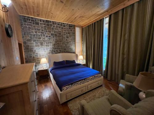 a bedroom with a bed with blue sheets and a stone wall at Alpine Home By HespakBNB in Dunga Gali