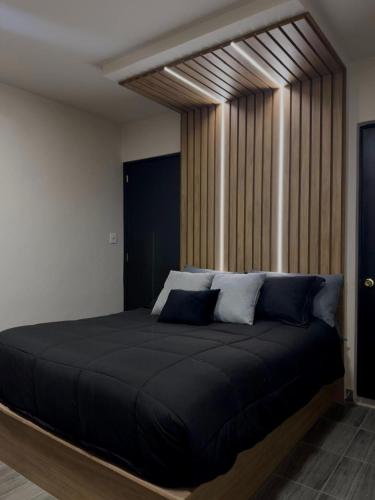 a bedroom with a large black bed with blue pillows at Loft oros in Oaxaca City