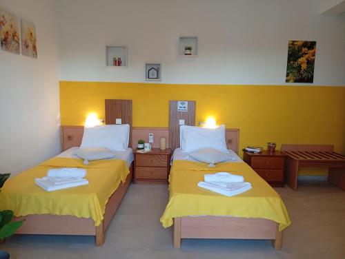 two beds in a room with yellow walls at on the STRIP apartment 4 in Kavos