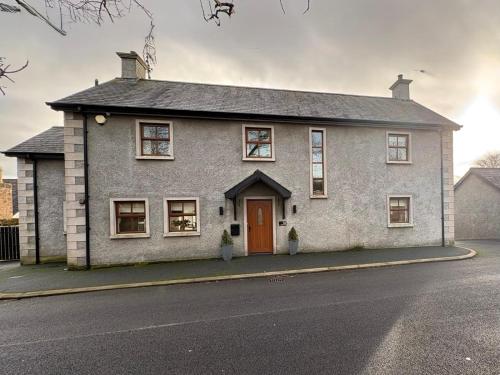 a white house with a red door on a street at Beech House in Antrim