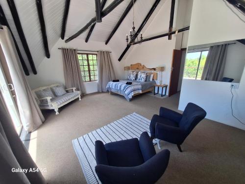 a large living room with blue chairs and a bed at The White House @ Cintsa in Chintsa