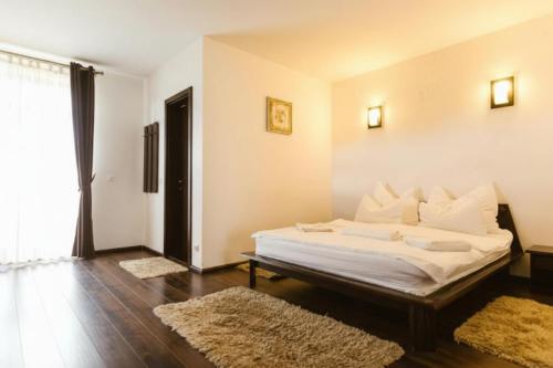a bedroom with a bed with white sheets and pillows at Hanul Conitei in Sovata