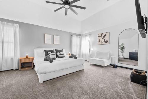 a white bedroom with a white couch and a ceiling fan at Elegant 5BR Pool House with Cinema Fire Pit and Games in Keller