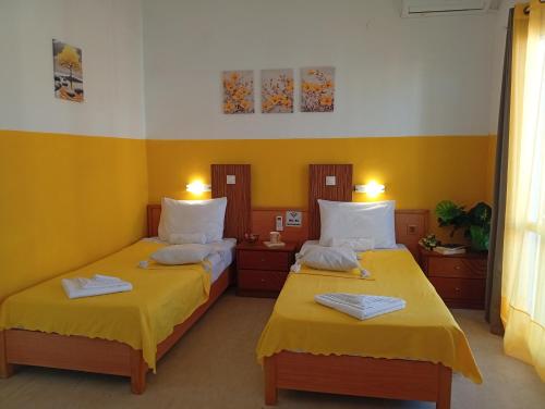 two beds in a room with yellow walls at on the STRIP-Studio 1 in Kavos