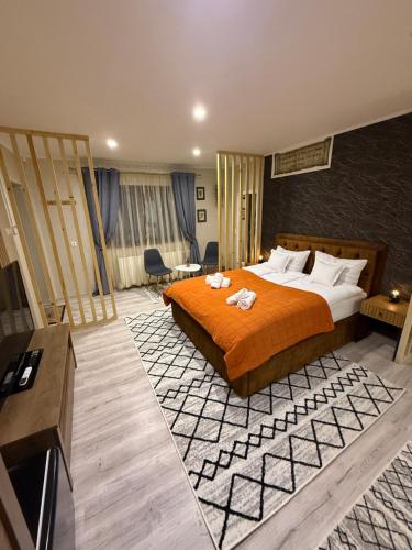 ein Hotelzimmer mit einem großen Bett mit orangefarbenen Laken in der Unterkunft Sofhia home in Târgu Mureș