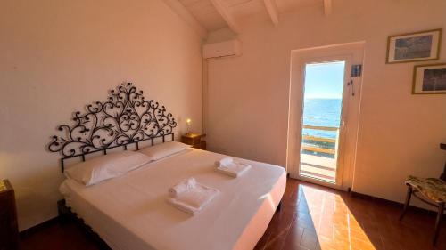 a bedroom with a large bed with a view of the ocean at S'Archittu Sunset House in S'archittu Cuglieri