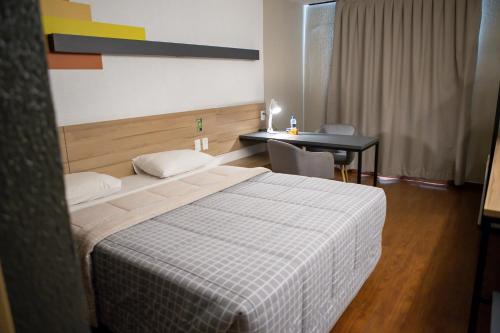 a hotel room with a bed and a desk at Hotel 10 Itajai/Navegantes in Itajaí
