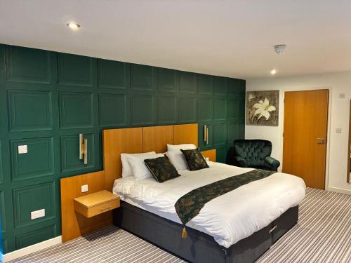 a bedroom with a bed and a green wall at Deangate Motel in Lydney