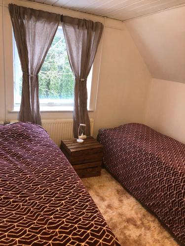 a bedroom with two beds and a window at Huset i Hammelev in Vojens