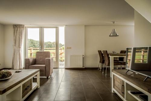 uma sala de estar com uma televisão e uma mesa e cadeiras em Het kleine Landgoed em Haarle