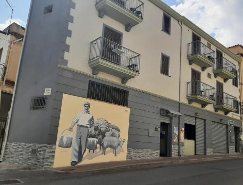 a mural of a man holding two buckets and sheep on a building at Affittacamere DOMO AGORA' in Tertenìa