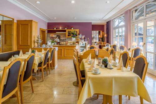 ein Restaurant mit Tischen und Stühlen und eine Küche in der Unterkunft Krone am Park - Gästehaus des Hotel Krone in Alzenau in Unterfranken