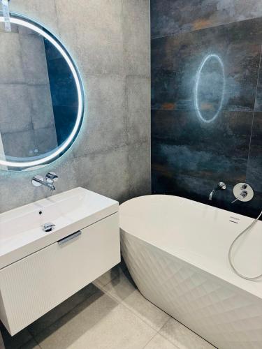 a bathroom with a sink and a tub and a mirror at Перлина Люкс in Khmelnytskyi