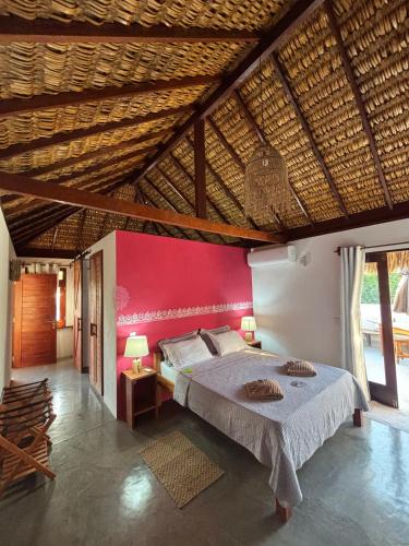 a bedroom with a large bed with a red wall at Pousada Lanea Experience in Atins
