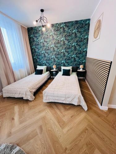 two beds in a room with a painting on the wall at Apartamenty Brzeska 10 in Warsaw