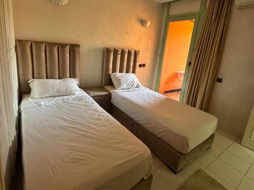 two beds in a small room with a window at Al ATLAS résidence in Marrakesh