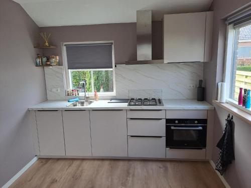 a kitchen with white cabinets and a sink and a window at Vakantiehuis in Oosterwolde