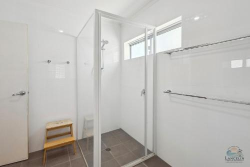 a glass shower door in a bathroom with a stool at Sea Chain in Lancelin