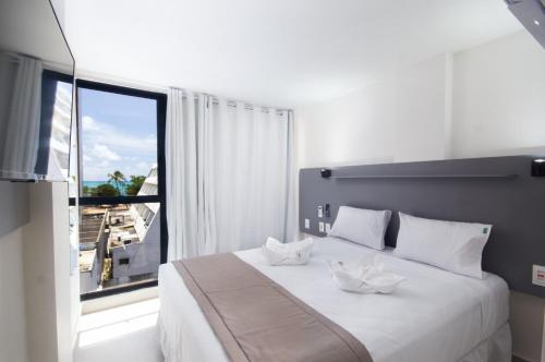 a bedroom with a white bed with a large window at Hotel Kazullo in Maceió