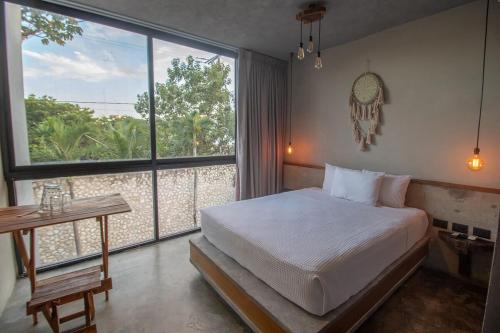a bedroom with a bed and a large window at condo pacha tulum in Tulum