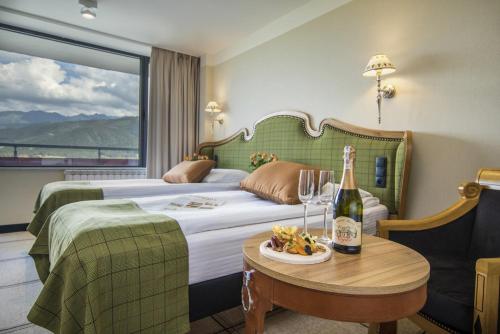 a hotel room with a bed and a table with a bottle of champagne at Bachleda Hotel Kasprowy in Zakopane