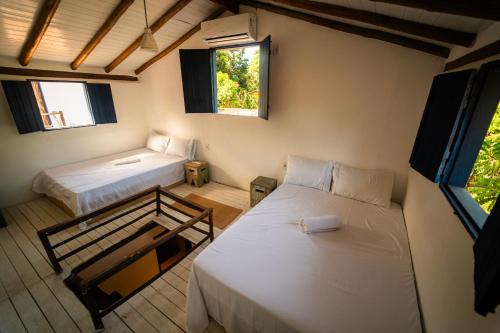 a room with two beds and two windows at Hostel Tainha Caraíva in Caraíva