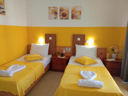 two beds in a room with yellow walls at on the STRIP-Studio 2 in Kavos