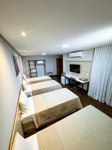 a hotel room with four beds and a television at Citi Executivo Hotel in Parnaíba