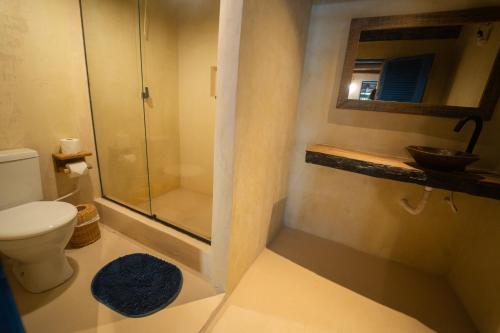 a bathroom with a shower and a toilet and a sink at Hostel Tainha Caraíva in Caraíva